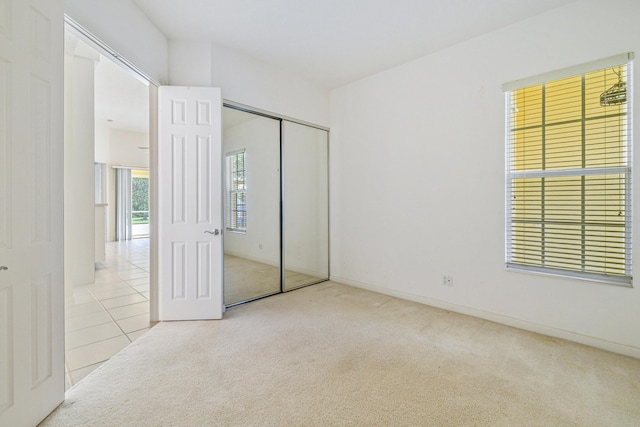 unfurnished bedroom featuring light carpet and a closet