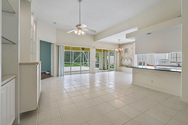 kitchen with ceiling fan with notable chandelier, sink, light tile patterned floors, a textured ceiling, and decorative light fixtures