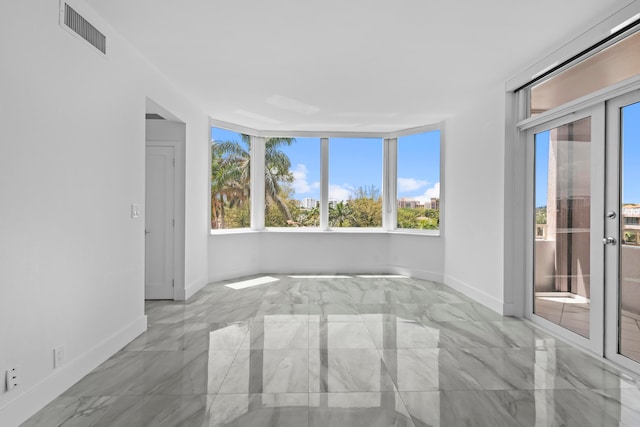 tiled spare room featuring a healthy amount of sunlight and french doors