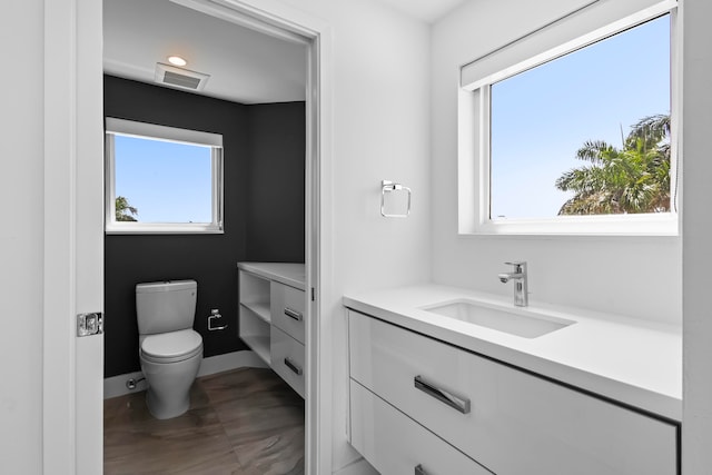 bathroom featuring tile patterned flooring, a healthy amount of sunlight, toilet, and vanity