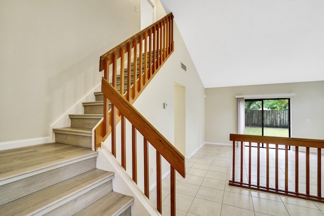 stairway featuring tile patterned flooring and high vaulted ceiling