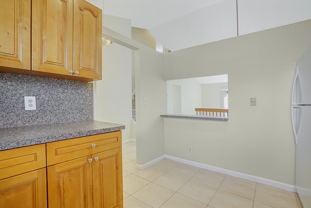 kitchen featuring decorative backsplash, white refrigerator, vaulted ceiling, and light tile patterned flooring