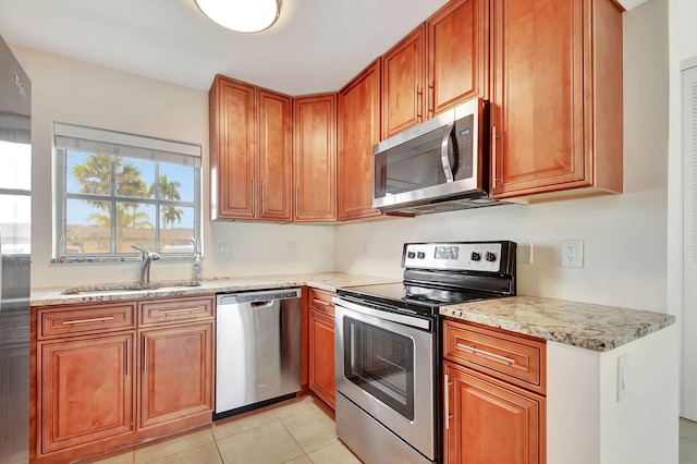 kitchen with light tile patterned flooring, light stone countertops, sink, and appliances with stainless steel finishes