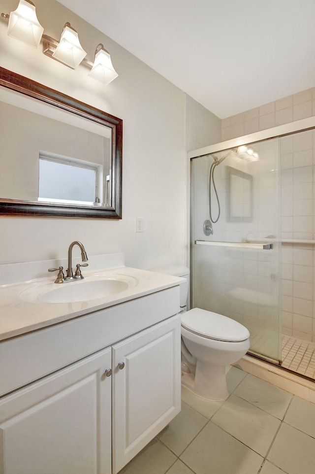 bathroom featuring tile patterned flooring, vanity, toilet, and a shower with door