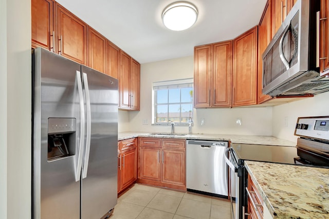 kitchen with light stone counters, sink, light tile patterned floors, and stainless steel appliances