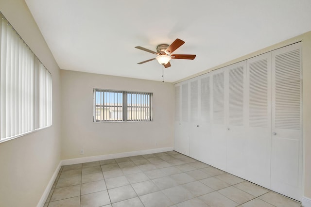 unfurnished bedroom with light tile patterned floors, a closet, and ceiling fan