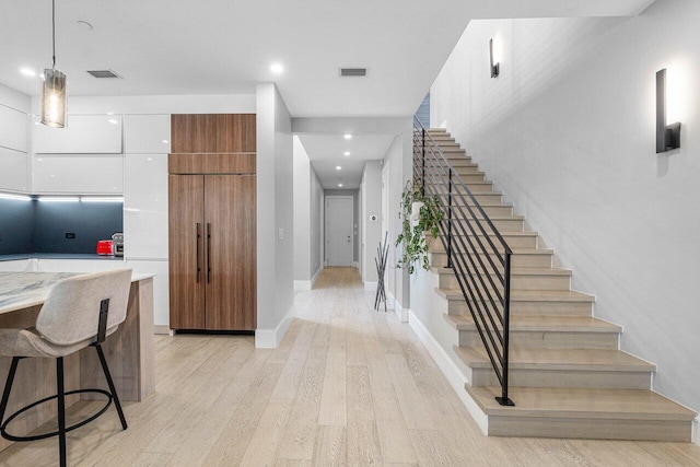 kitchen with white cabinetry, a kitchen breakfast bar, light hardwood / wood-style floors, and decorative light fixtures