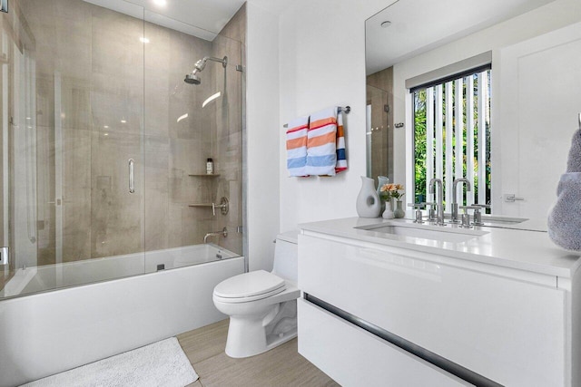 full bathroom featuring bath / shower combo with glass door, toilet, and vanity