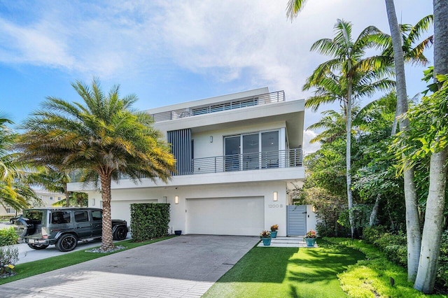 view of front of home with decorative driveway, stucco siding, a balcony, a garage, and a front lawn