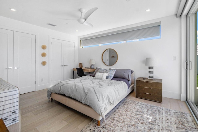 bedroom featuring light wood finished floors, two closets, visible vents, and recessed lighting