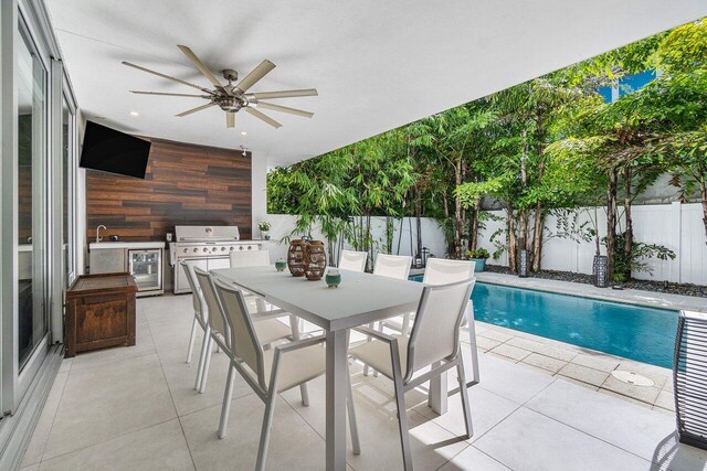 view of patio featuring an outdoor kitchen, sink, a fenced in pool, a grill, and ceiling fan