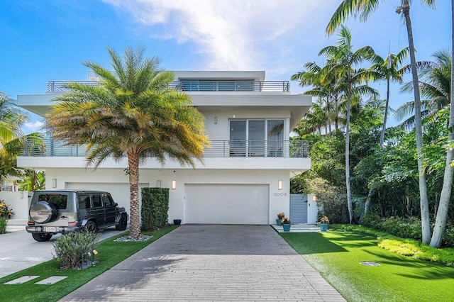 view of front of property with a balcony, a front lawn, decorative driveway, and stucco siding