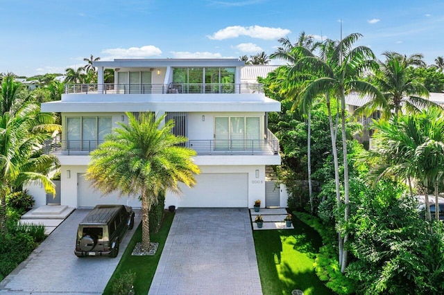 view of front of home featuring a balcony, a garage, decorative driveway, and stucco siding