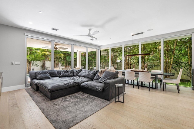 living room with light wood-type flooring, ceiling fan, visible vents, and baseboards