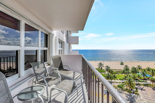 balcony with a water view and a view of the beach