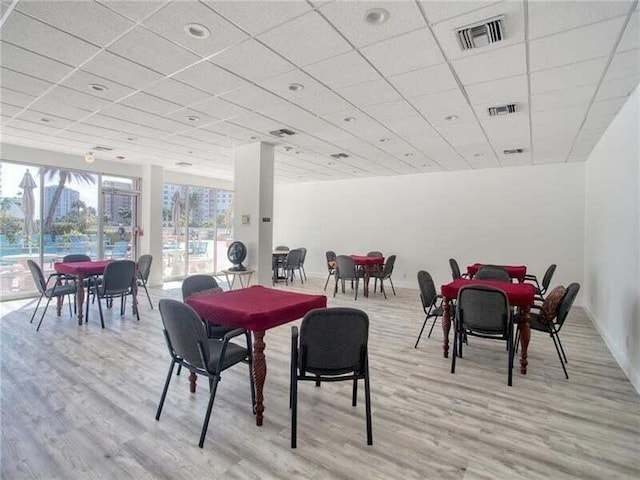 dining room with light wood-type flooring and a paneled ceiling