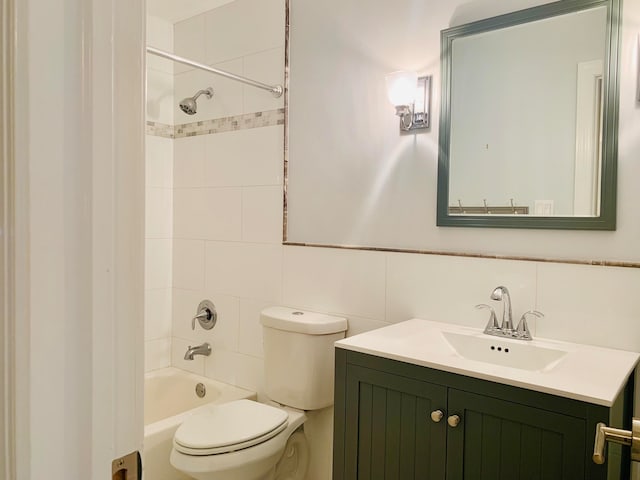 full bathroom with tile walls, toilet, vanity, and tiled shower / bath