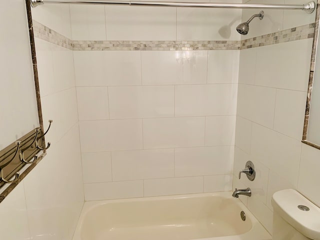 bathroom featuring tiled shower / bath combo and toilet