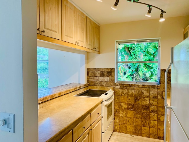 kitchen with light brown cabinetry, rail lighting, light wood-type flooring, and white appliances