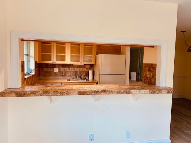 kitchen with a breakfast bar, sink, white refrigerator, and backsplash