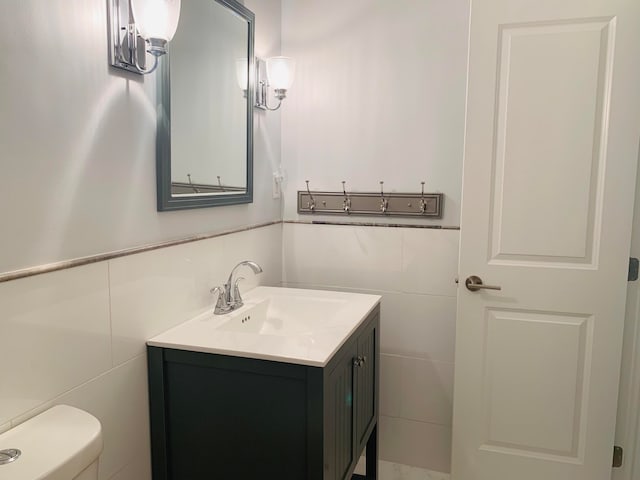 bathroom featuring vanity, tile walls, and toilet