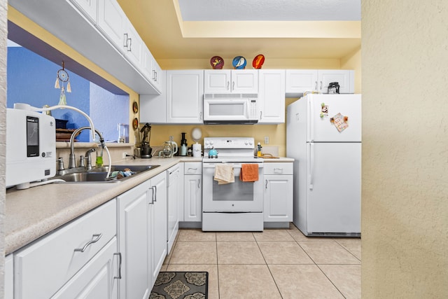 kitchen with sink, light tile patterned flooring, white cabinets, and white appliances