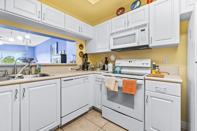 kitchen featuring light tile patterned flooring, hanging light fixtures, white cabinets, white appliances, and sink