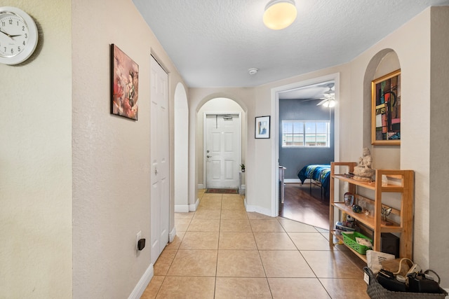 hall featuring light tile patterned floors and a textured ceiling