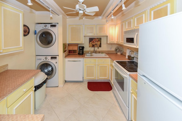 kitchen with white appliances, sink, light tile patterned floors, stacked washing maching and dryer, and ceiling fan