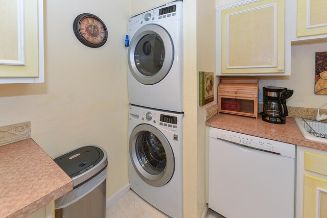 clothes washing area featuring stacked washer and dryer and light tile patterned flooring