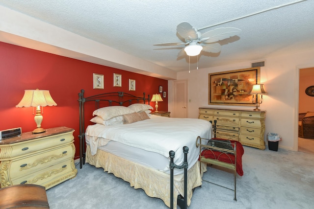 bedroom with a textured ceiling, carpet floors, ceiling fan, and visible vents