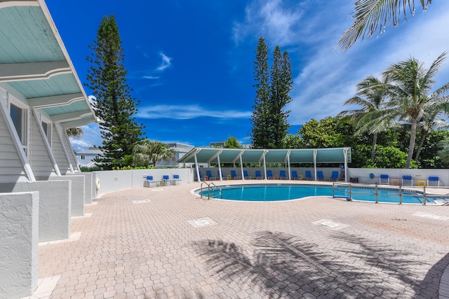 community pool with a patio area and fence