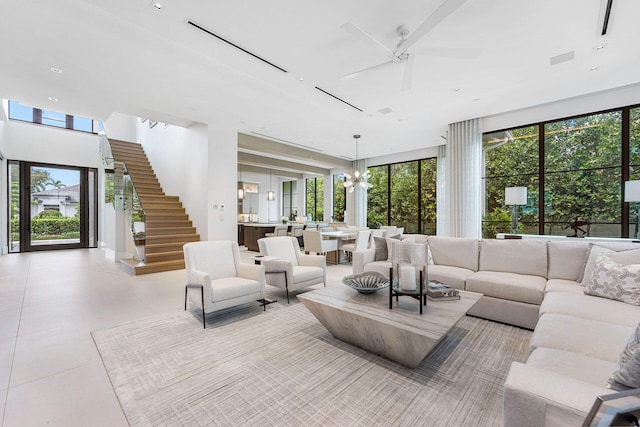 tiled living room with ceiling fan with notable chandelier and a wealth of natural light