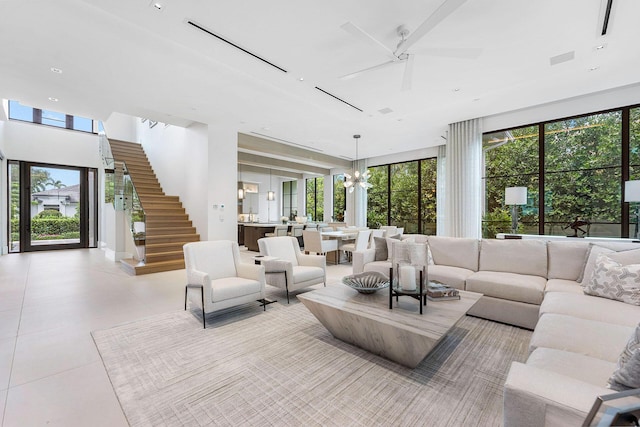 living room featuring light tile patterned flooring, a healthy amount of sunlight, and ceiling fan with notable chandelier