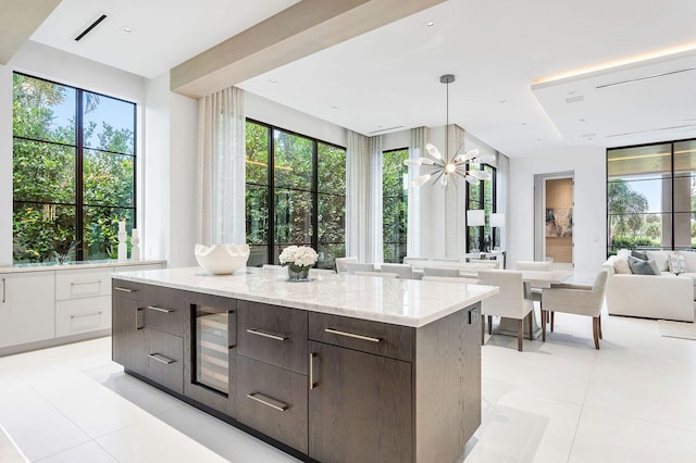 kitchen featuring dark brown cabinetry, beverage cooler, a wealth of natural light, and white cabinetry