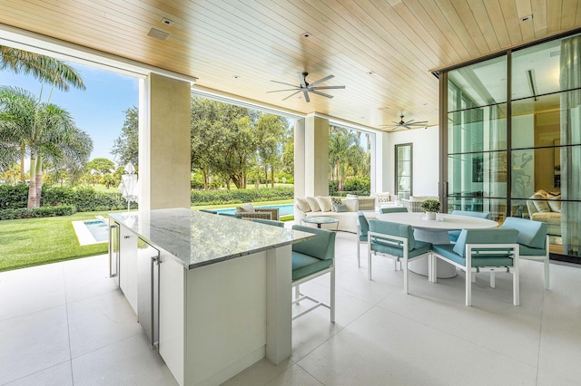 view of patio / terrace featuring ceiling fan, a pool, and an outdoor bar