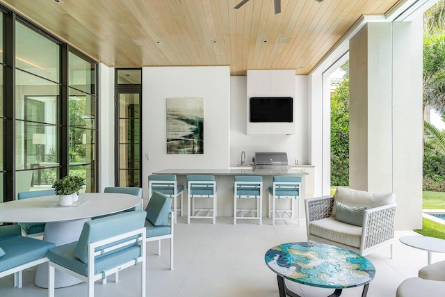 view of patio with ceiling fan, a grill, an outdoor kitchen, and a wet bar