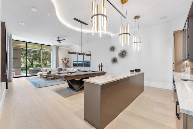 kitchen with light stone counters, pendant lighting, ceiling fan, light hardwood / wood-style flooring, and floor to ceiling windows