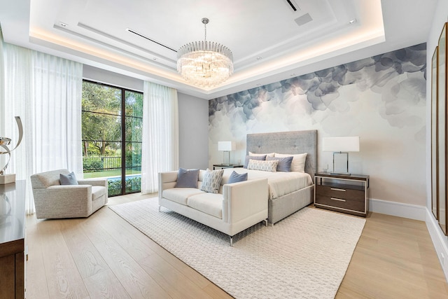 bedroom featuring a raised ceiling, light hardwood / wood-style floors, and a notable chandelier