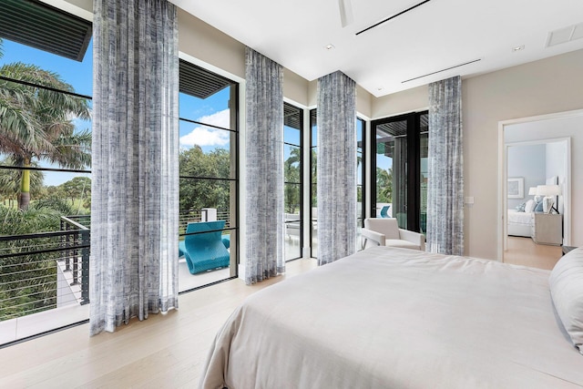 bedroom featuring access to exterior, multiple windows, and light wood-type flooring