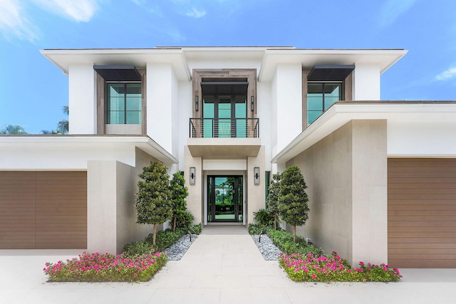 view of exterior entry with a garage and a balcony