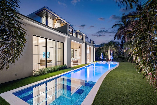 pool at dusk featuring a lawn