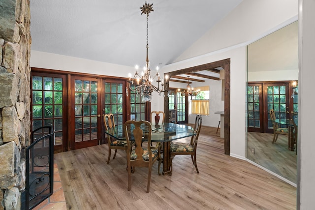 dining room featuring light wood-type flooring, a chandelier, vaulted ceiling with beams, and french doors