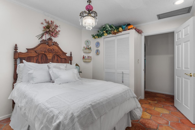 bedroom with a textured ceiling, crown molding, a closet, and tile patterned floors