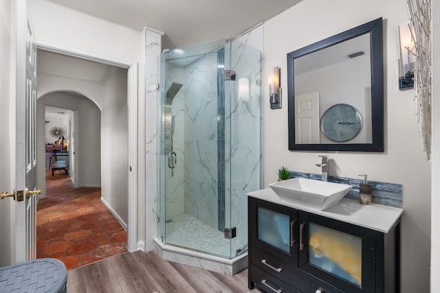 bathroom featuring wood-type flooring, vanity, and a shower with shower door