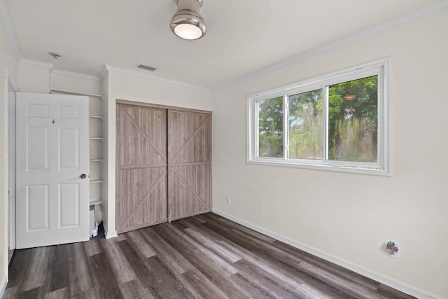 unfurnished bedroom with crown molding, dark wood-type flooring, and a closet