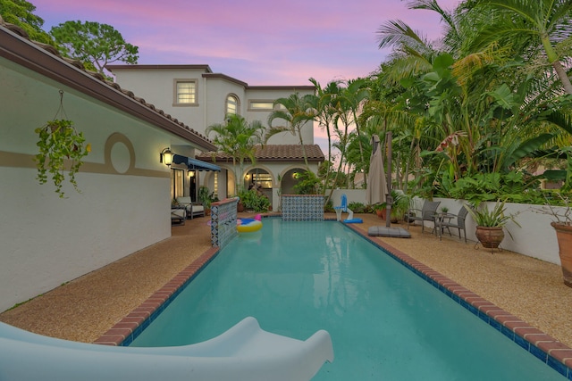 pool at dusk featuring a patio