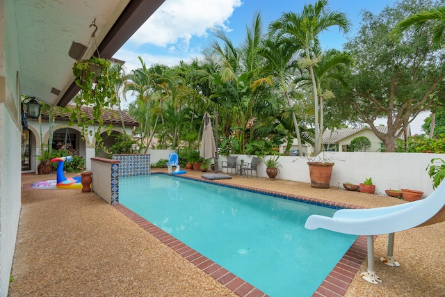 view of swimming pool featuring a water slide and a patio area