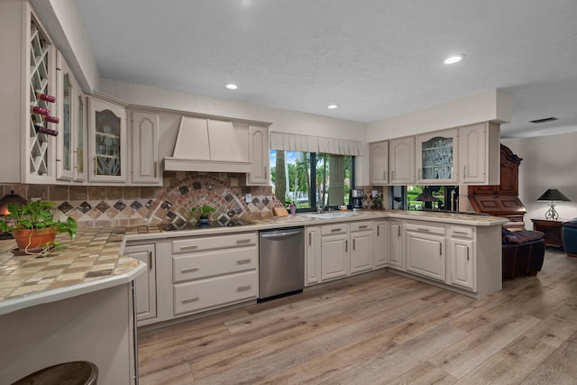 kitchen featuring dishwasher, custom range hood, light wood-type flooring, and kitchen peninsula