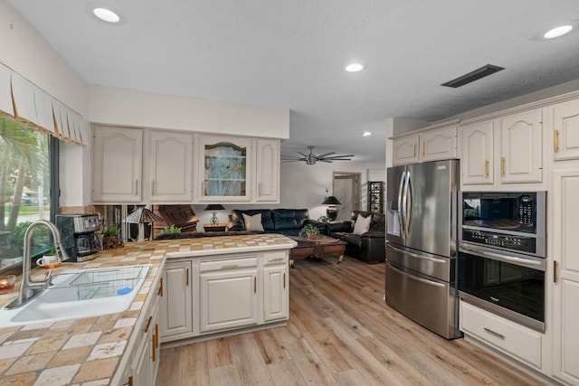 kitchen featuring appliances with stainless steel finishes, tile countertops, sink, and ceiling fan